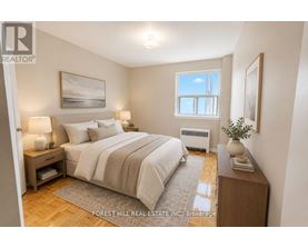 A bedroom with a large bed, a nightstand, and a window.