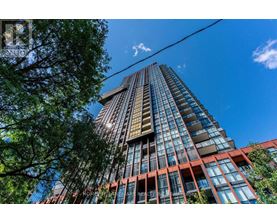 A tall building with a glass facade stands under a clear blue sky.