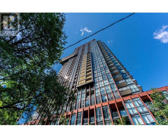 A tall building with a glass facade stands under a clear blue sky.