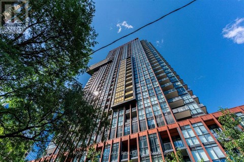 A tall building with a glass facade stands under a clear blue sky.