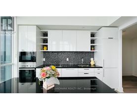 A modern kitchen with white cabinets and a black countertop.