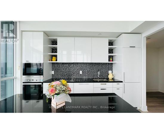 A modern kitchen with white cabinets and a black countertop.