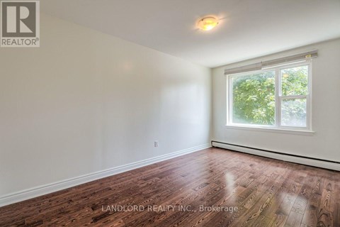 A room with a window and wooden flooring.