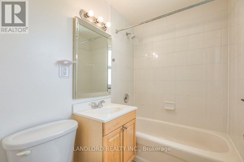 A white bathroom with a tub, sink and mirror.