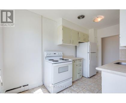 A white kitchen with a stove, oven, and refrigerator.