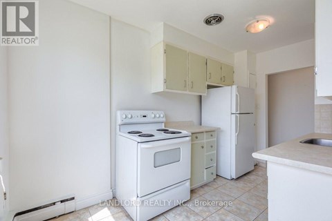 A white kitchen with a stove, oven, and refrigerator.