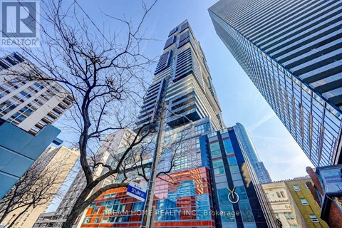 A tall building with a glass facade stands in the middle of a cityscape.