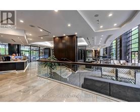 A modern office space with a reception desk and a staircase leading to the upper floor.