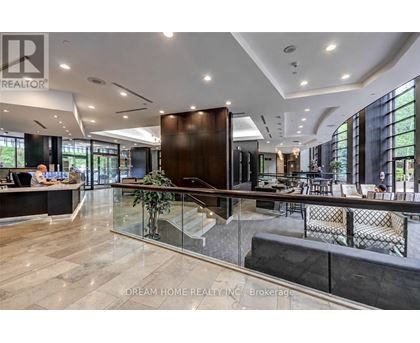 A modern office space with a reception desk and a staircase leading to the upper floor.