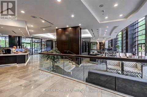 A modern office space with a reception desk and a staircase leading to the upper floor.