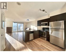 A modern kitchen with stainless steel appliances and wooden flooring.
