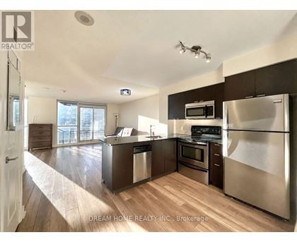 A modern kitchen with stainless steel appliances and wooden flooring.