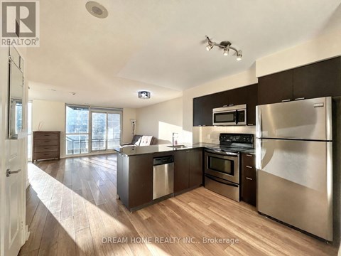 A modern kitchen with stainless steel appliances and wooden flooring.