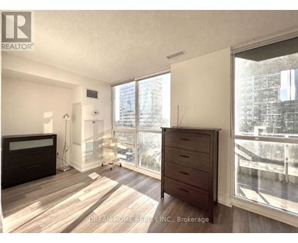 A bedroom with a large window and a wooden floor.