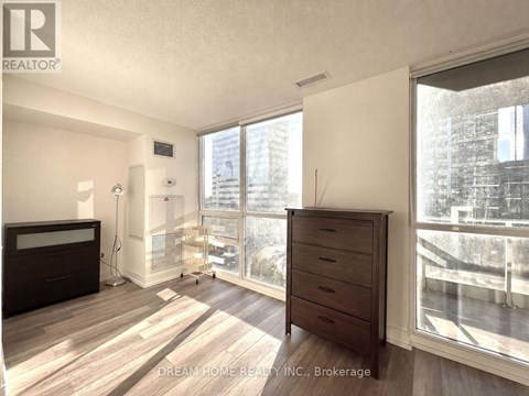 A bedroom with a large window and a wooden floor.