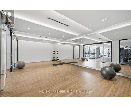 A spacious room with wooden floors and mirrors on the wall.