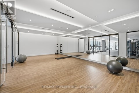 A spacious room with wooden floors and mirrors on the wall.