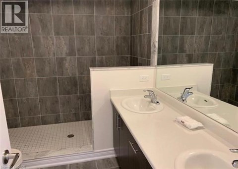 A bathroom with a sink, mirror, and shower.