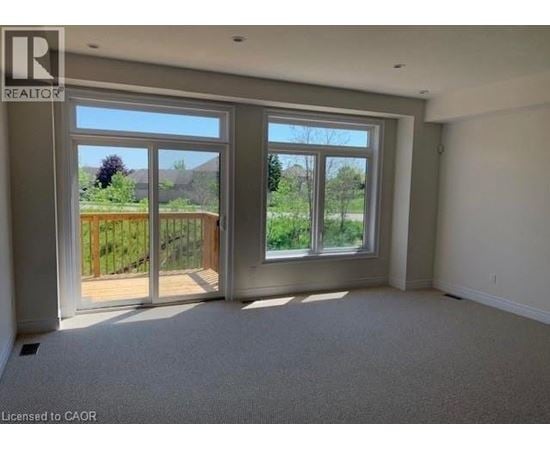 A room with a large window and a sliding glass door leading to a backyard.