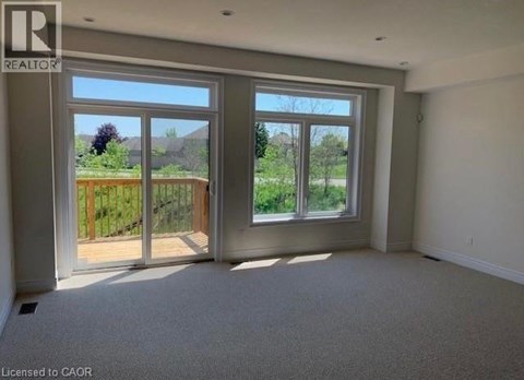 A room with a large window and a sliding glass door leading to a backyard.