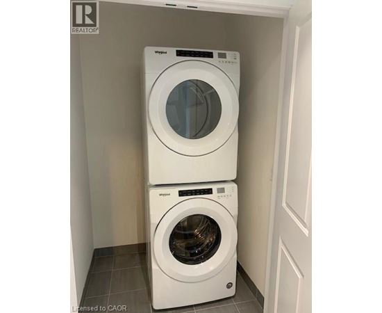 Two white front load washing machines stacked on top of each other in a laundry room.