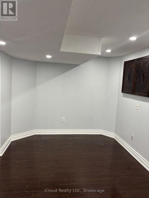 A room with white walls and dark wood flooring.