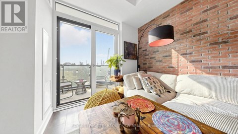A living room with a white couch and a brick wall.