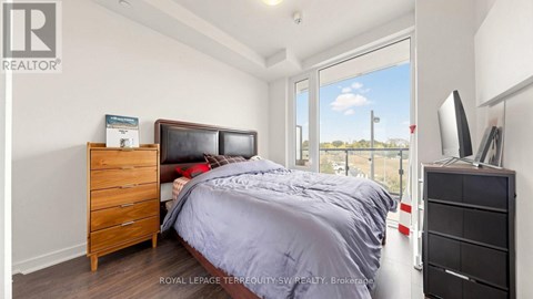 A bedroom with a bed, dresser, and a window overlooking a field.