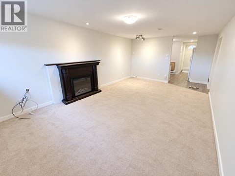 A living room with a fireplace and carpeted floor.
