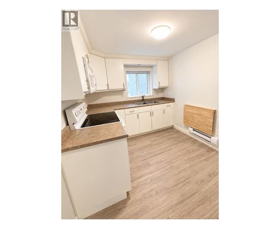 A kitchen with white cabinets and a wooden floor.