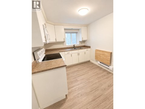 A kitchen with white cabinets and a wooden floor.