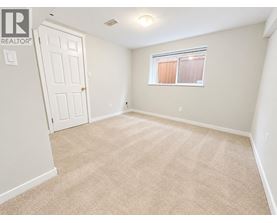 A bedroom with a carpeted floor and a window with blinds.