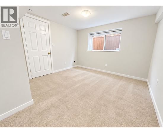 A bedroom with a carpeted floor and a window with blinds.