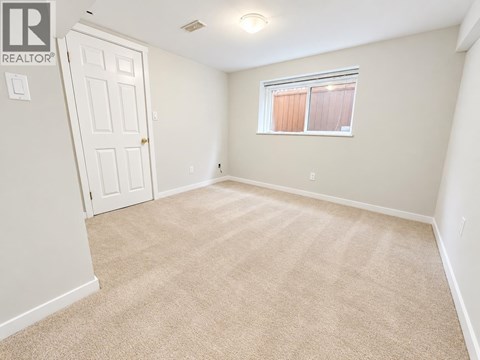 A bedroom with a carpeted floor and a window with blinds.