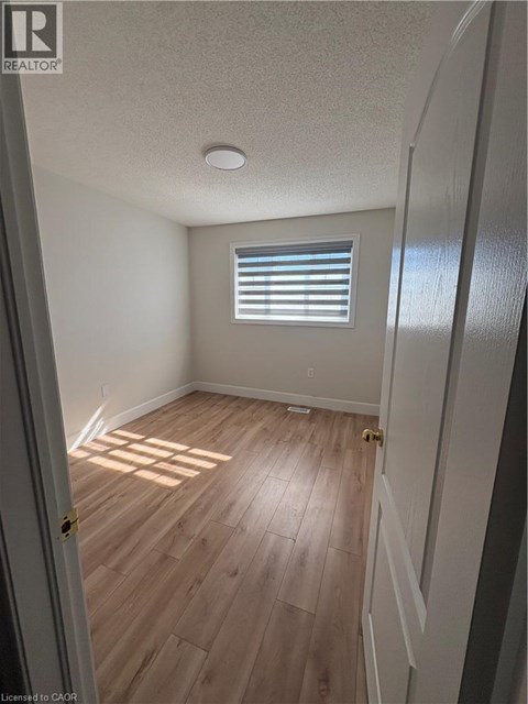 A room with wooden flooring and a window with blinds.