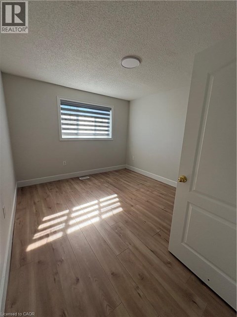 A room with wooden flooring and a window letting in sunlight.