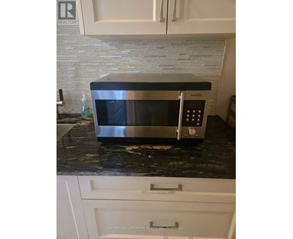 A silver microwave oven sitting on a black granite countertop.