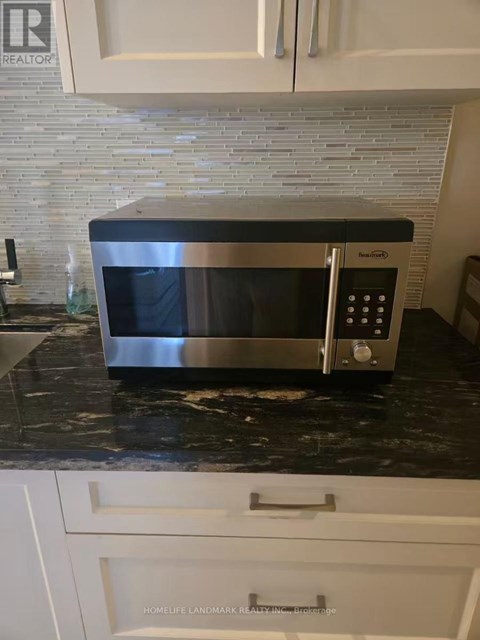 A silver microwave oven sitting on a black granite countertop.