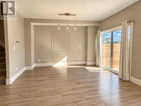 A spacious room with wooden floors and a large window.