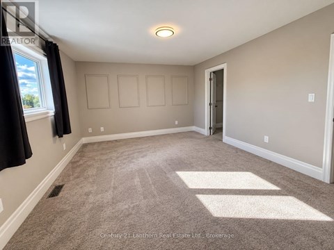 A room with a carpeted floor and a window with curtains.