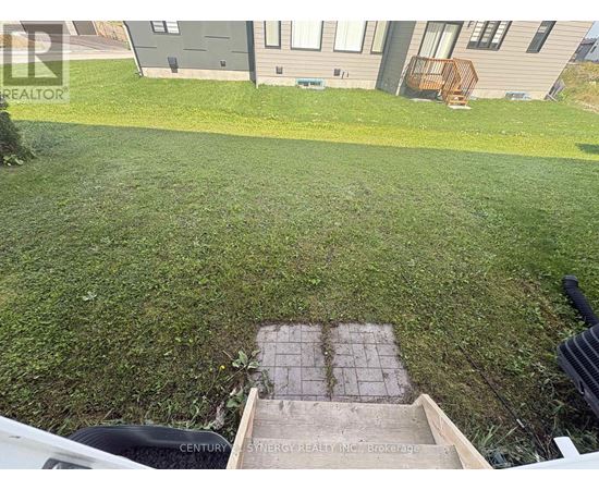 A well-maintained lawn in front of a house with a brick pathway leading to a small garden area.