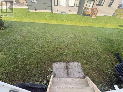 A well-maintained lawn in front of a house with a brick pathway leading to a small garden area.