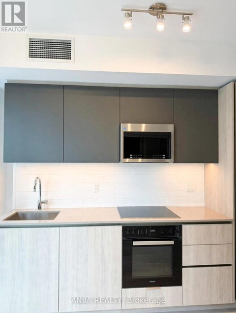 A modern kitchen with a stainless steel oven and white cabinets.