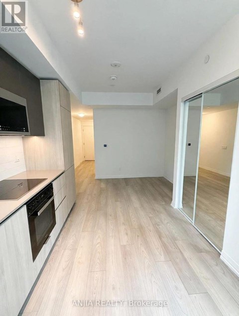 A modern kitchen with wooden flooring and a glass door leading to another room.
