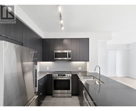 A modern kitchen with dark wood cabinets and stainless steel appliances.
