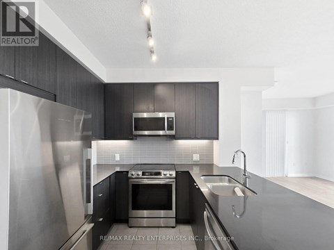 A modern kitchen with dark wood cabinets and stainless steel appliances.
