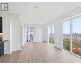 A spacious room with wooden floors and large windows overlooking a cityscape.