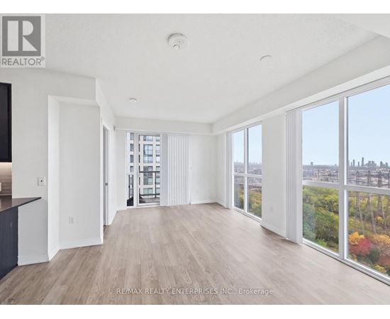 A spacious room with wooden floors and large windows overlooking a cityscape.