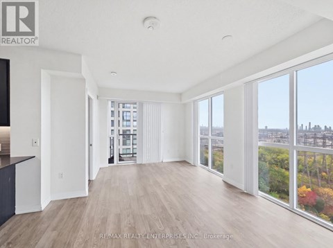 A spacious room with wooden floors and large windows overlooking a cityscape.
