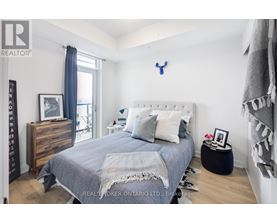 A bedroom with a bed, nightstand, and a dresser with a mirror.